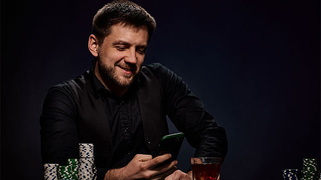 man sitting at roulette table on phone and gambling